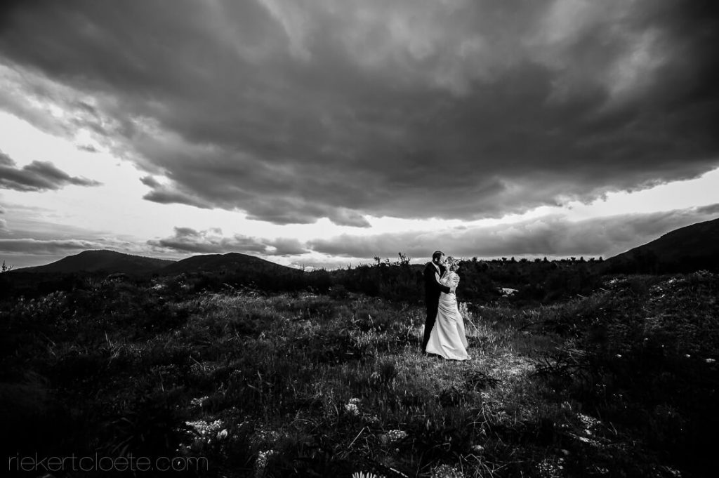 Wedding couple in a field with dark clouds