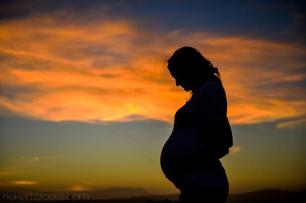 Silhouette of pregnant mother in the sunset