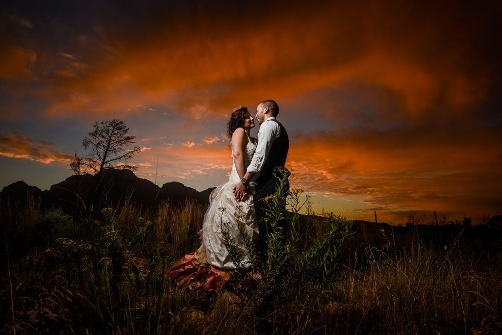 Wedding couple kissing, sunset background