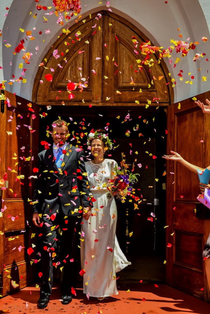 Bride and groom leaving church thrown with flower petals