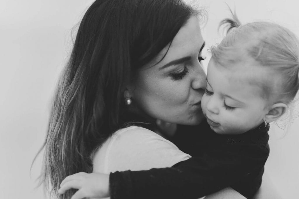 Mom kissing daughter