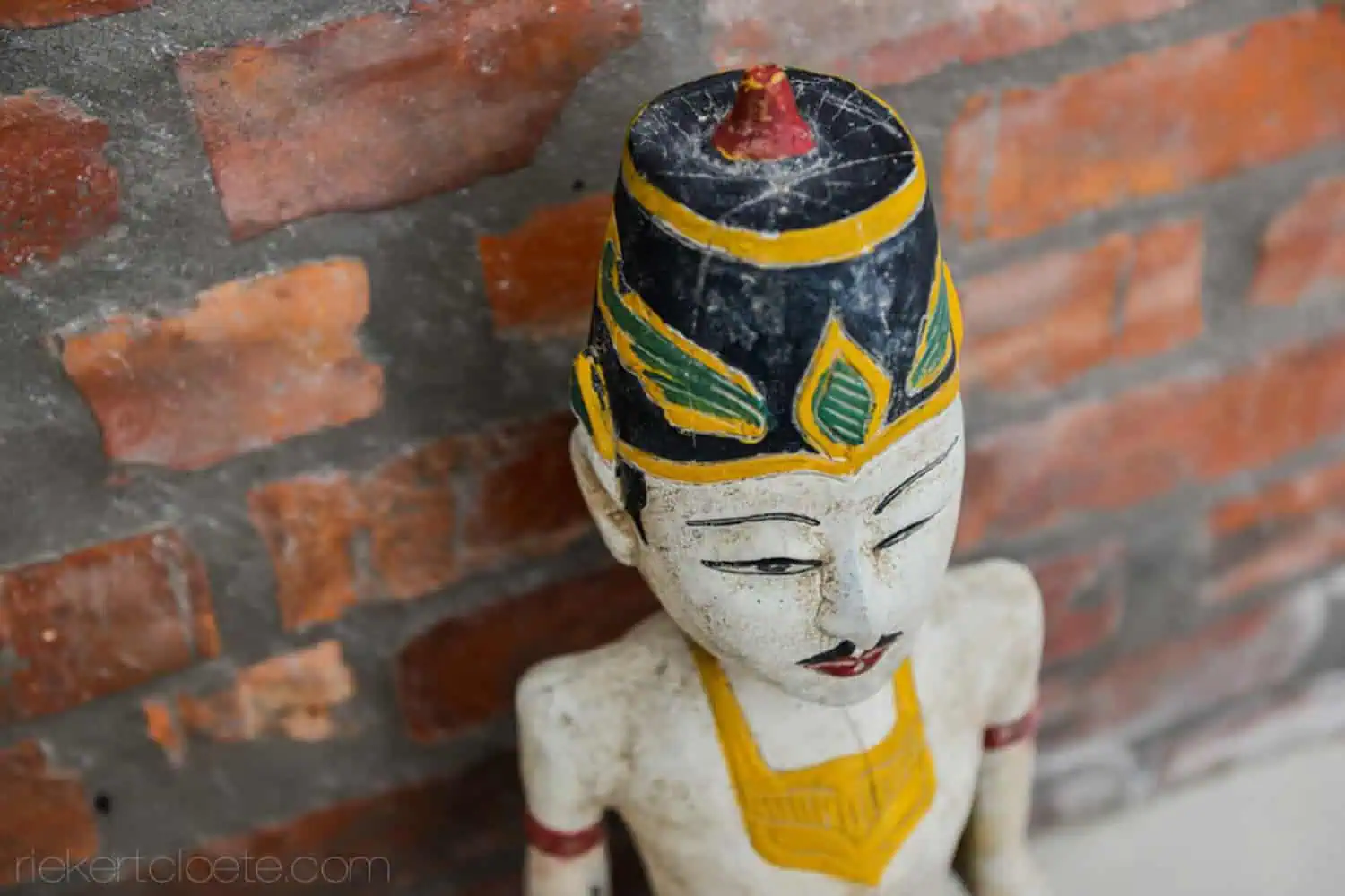 carved wooden figurine brick wall product photography durbanville