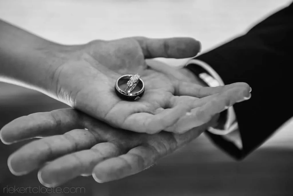 black white couple hands holding wedding rings