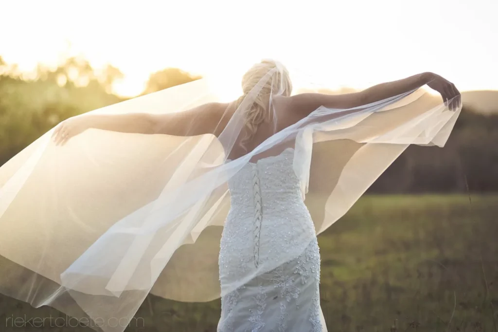 bride backless lace gown spread arms veil golden hour