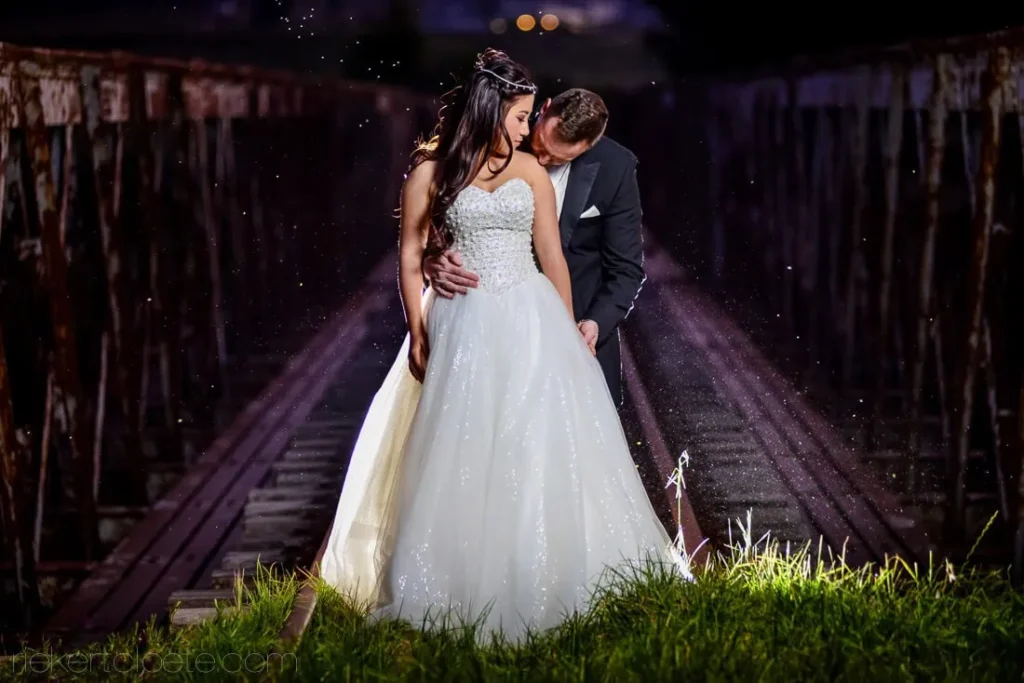 bride ballgown groom wooden bridge night rain