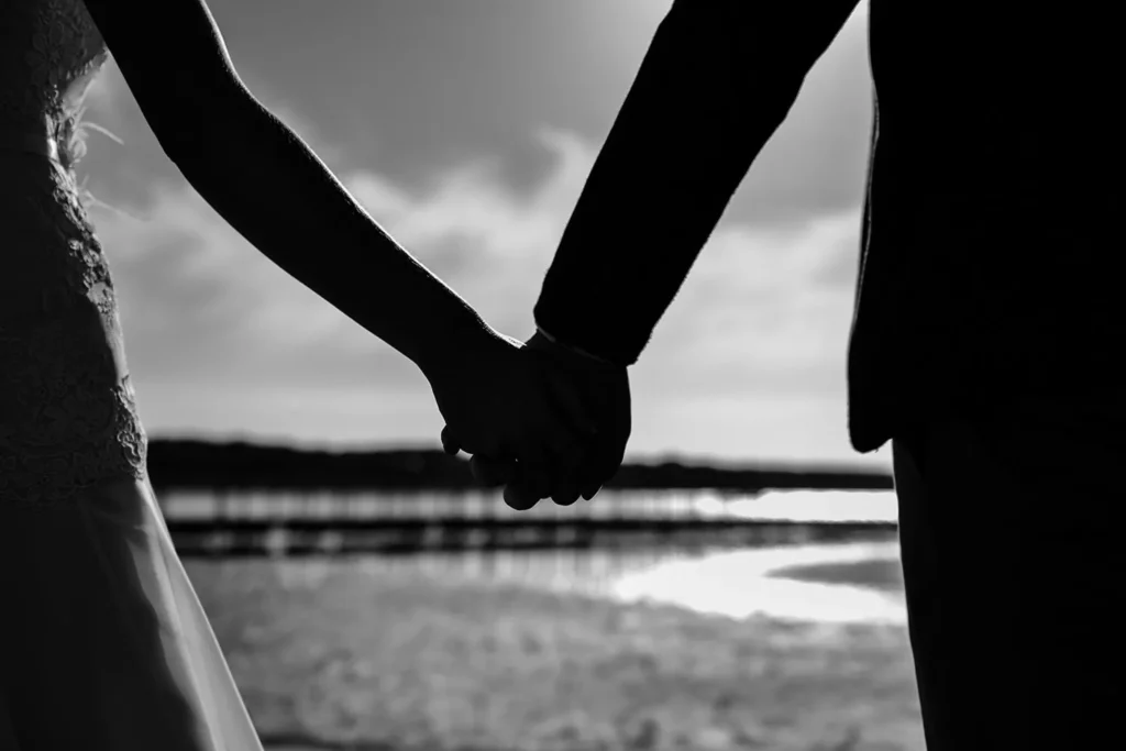 bride groom holding hands silhouette black white beach