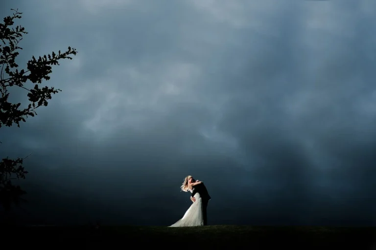 bride groom kiss dramatic storm clouds grassy field