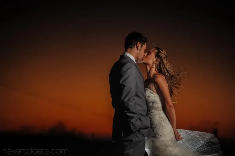 bride groom kiss fiery orange sunset winelands