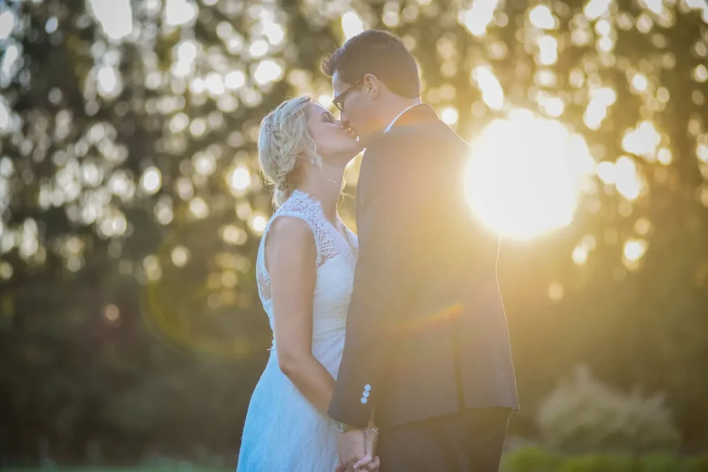 bride groom kissing golden hour sunlight trees