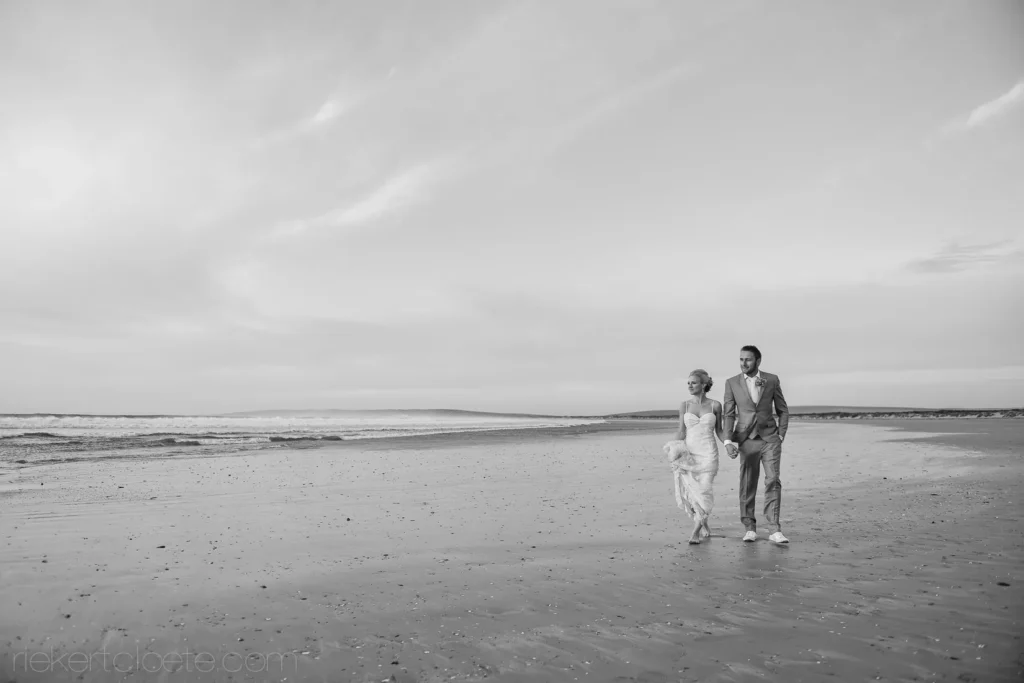 bride groom walking sandy beach ocean waves