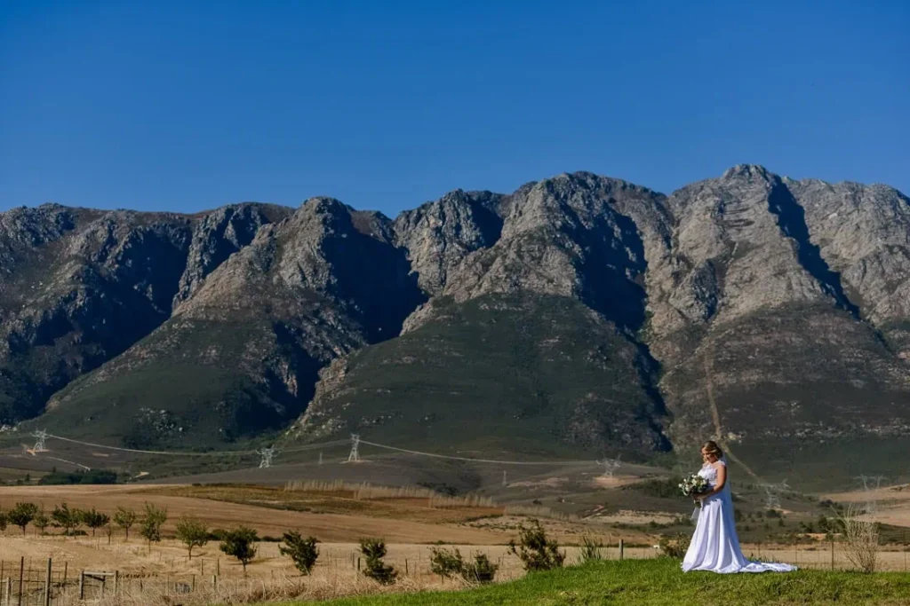 bride holding bouquet open field mountain range