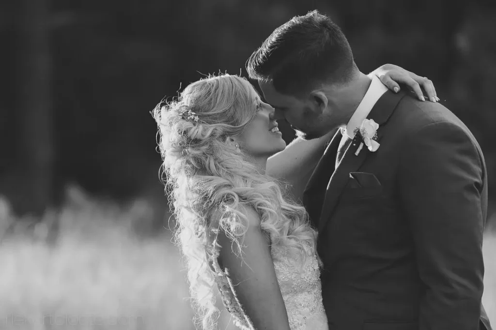 bride laughing groom embrace outdoor field bw