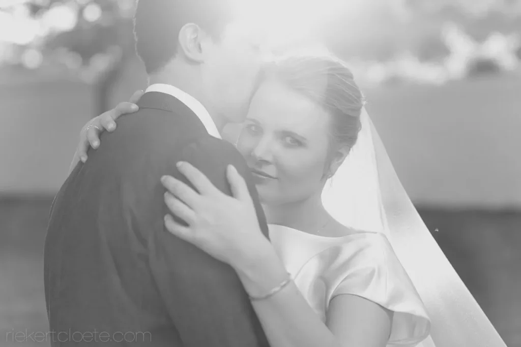 bride looking over shoulder groom embrace bw
