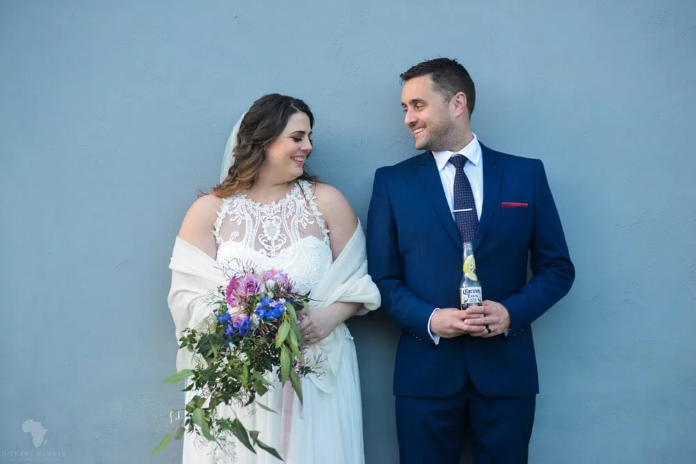bride purple bouquet groom navy suit blue wall
