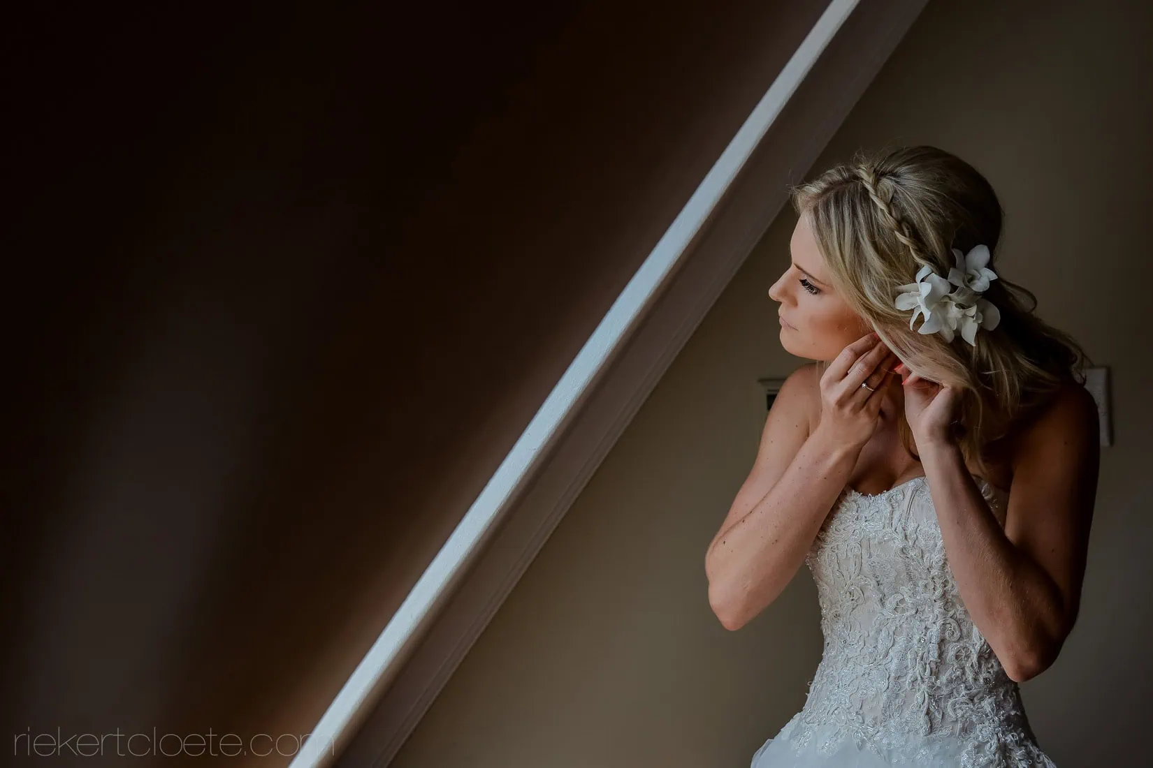 bride putting on earring floral hair accessory