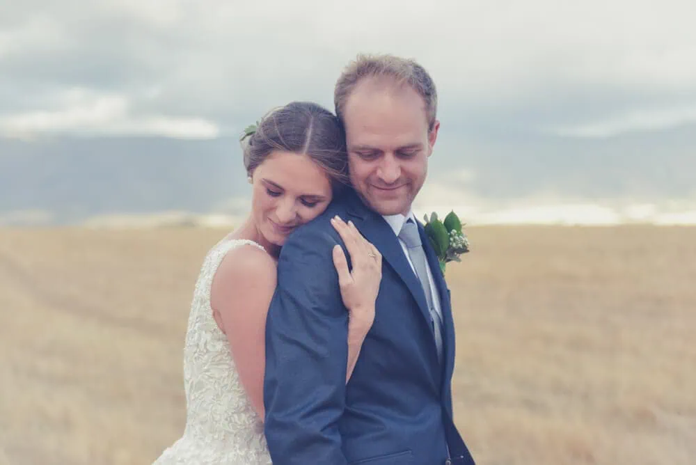 bride rests head on groom chest wheat field overcast