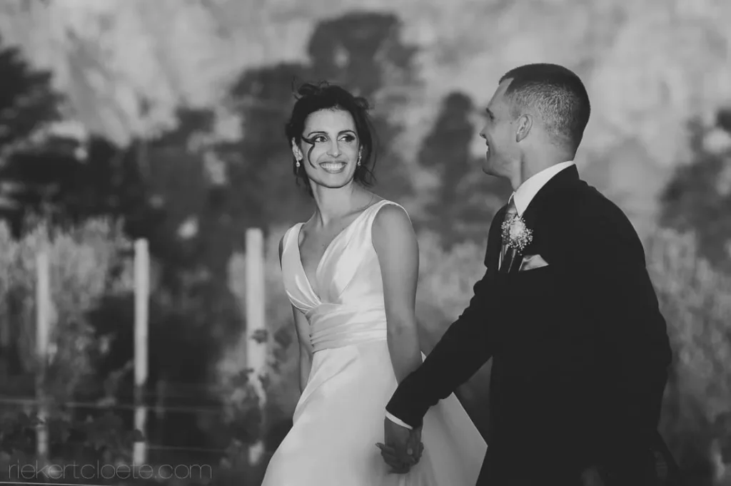bride smiling back groom garden black white