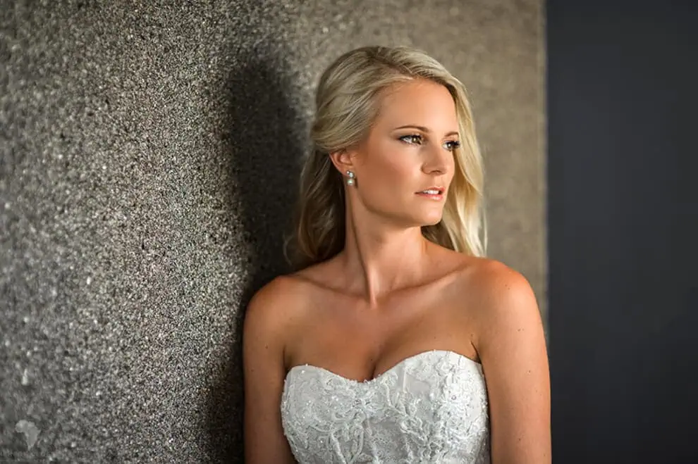 bride strapless lace gown leaning stone wall