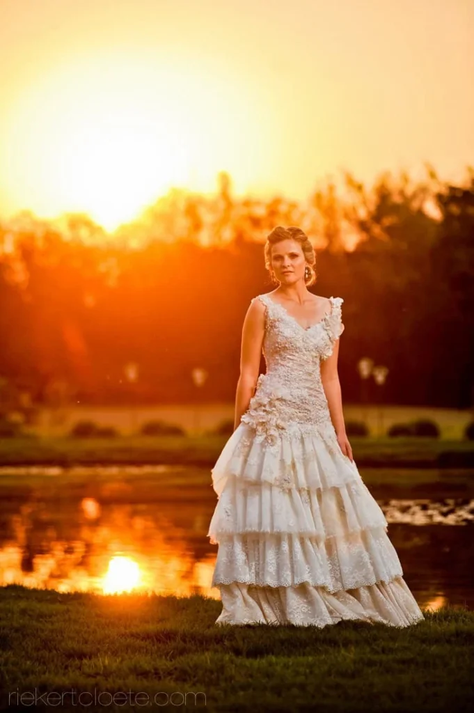 bride tiered lace gown golden sunset garden pond