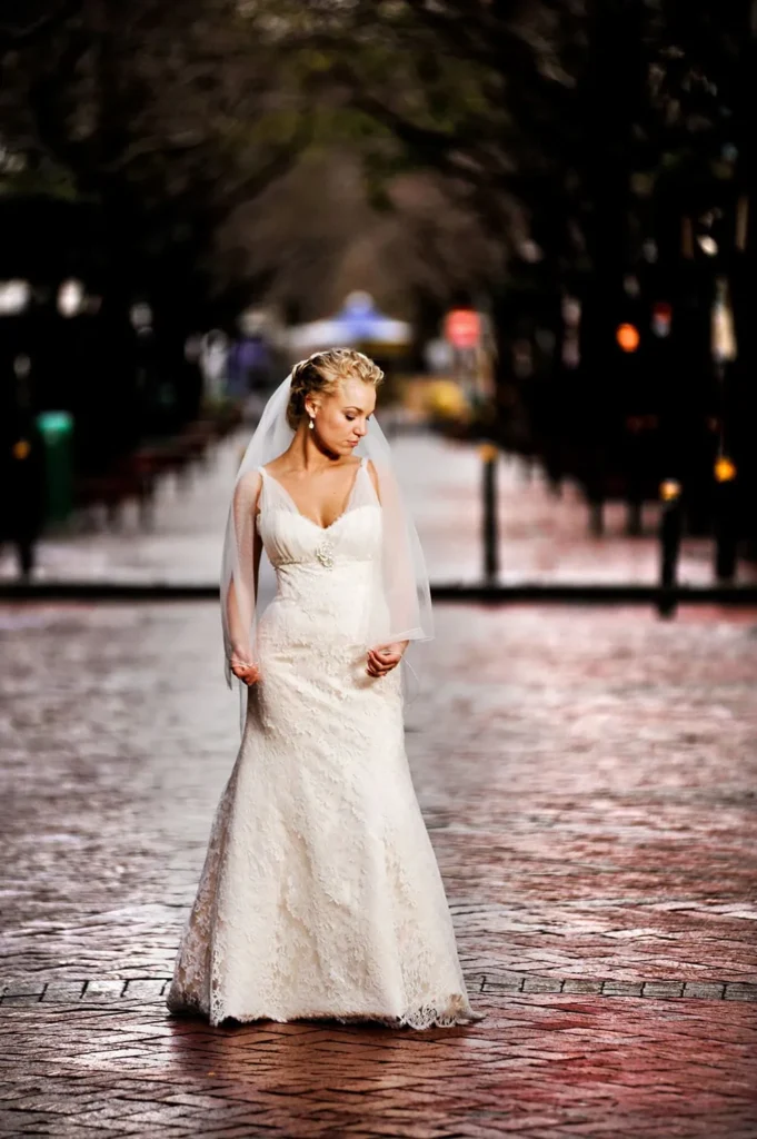bride walking rainy cobblestone street full length