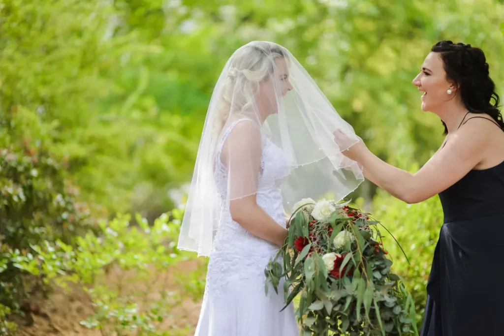 bridesmaid lifting veil bride rose bouquet garden