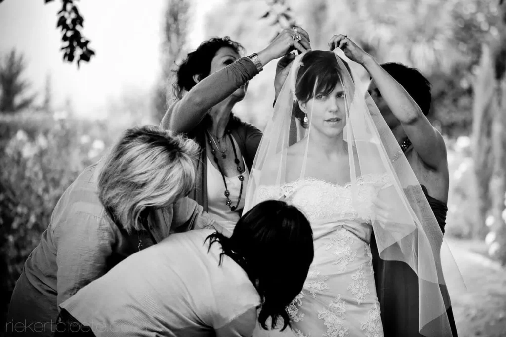 bridesmaids attaching bridal veil outdoor preparations