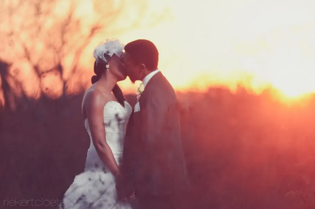 close up couple kiss fiery orange bokeh sunset