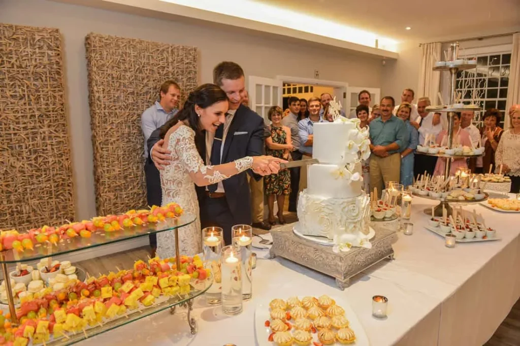 couple cutting tiered wedding cake reception