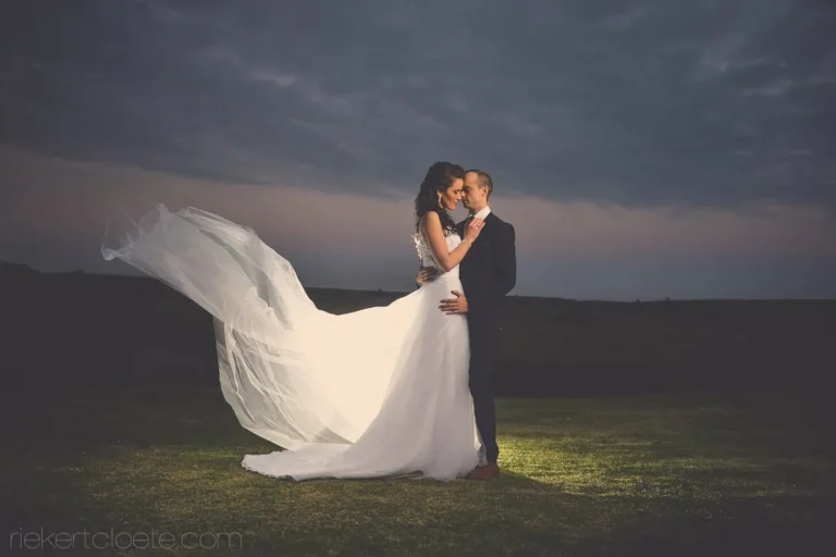 couple embrace veil flowing hilltop dark clouds