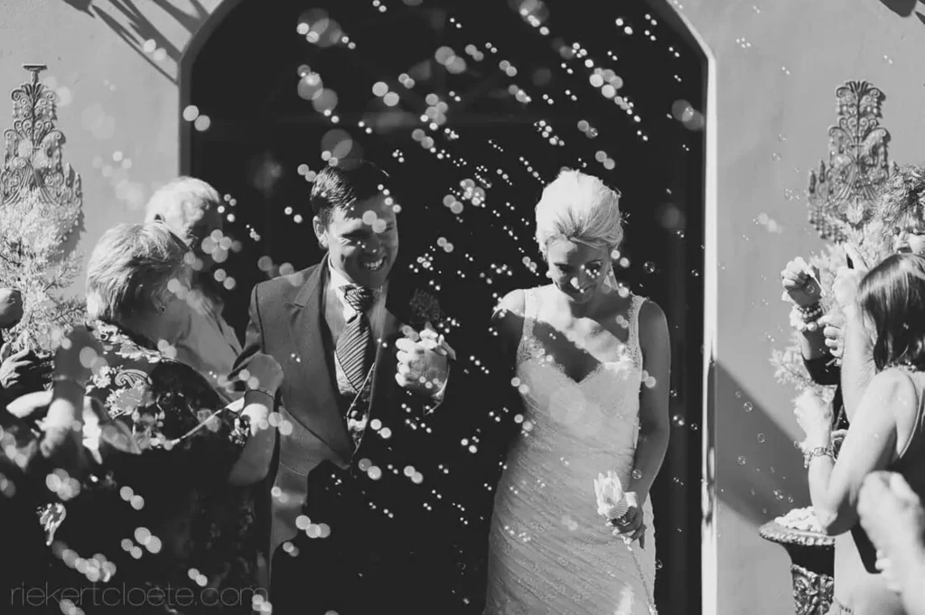 couple exiting church confetti bubbles ornate entrance