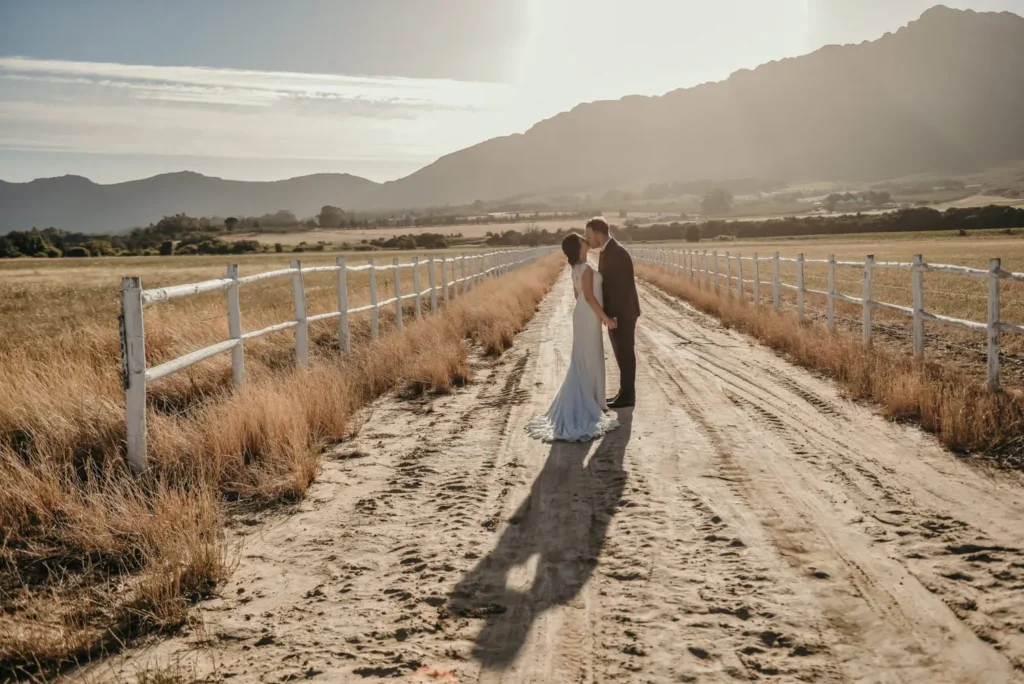 couple kiss farm road white fence mountains