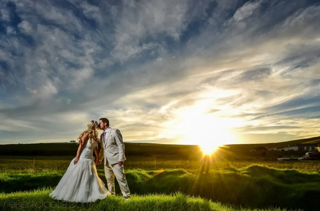 couple kiss green field rolling hills sunset