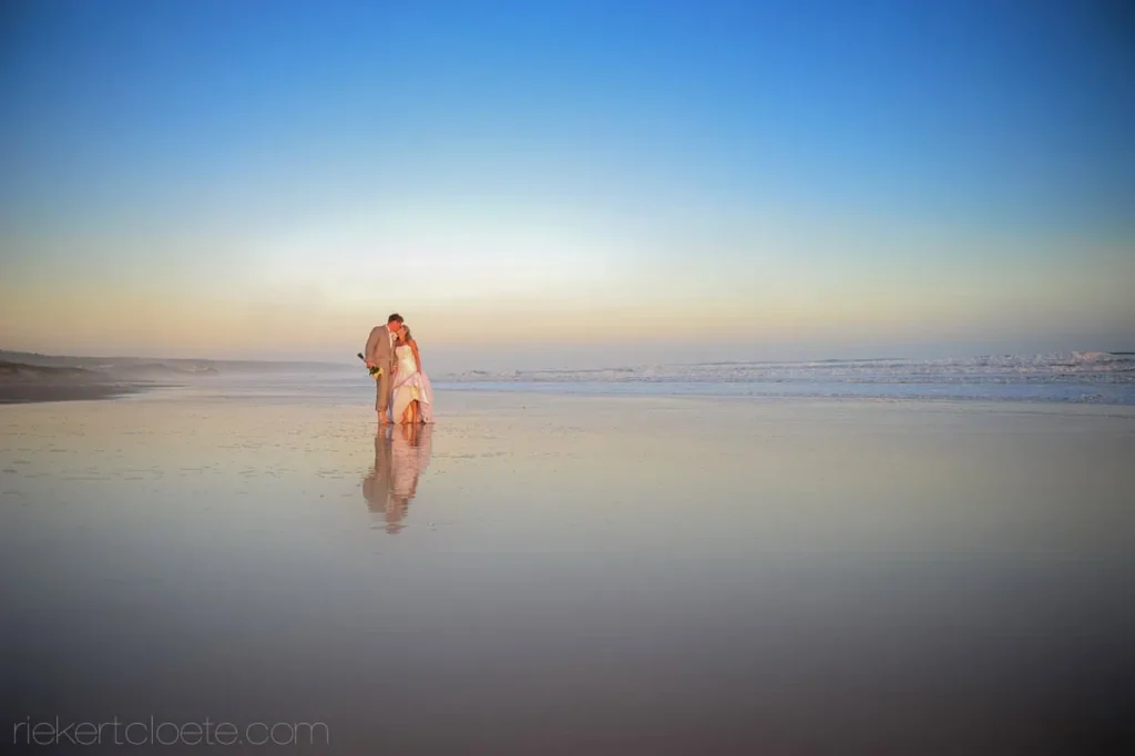 couple kissing beach sunset reflection wet sand