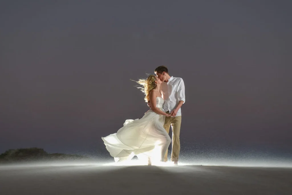 couple kissing beach windswept dress hair night