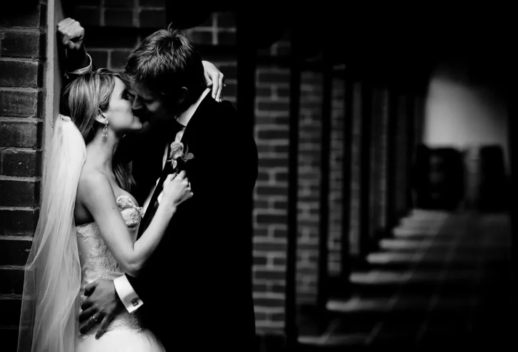 couple kissing brick wall arched corridor portrait bw