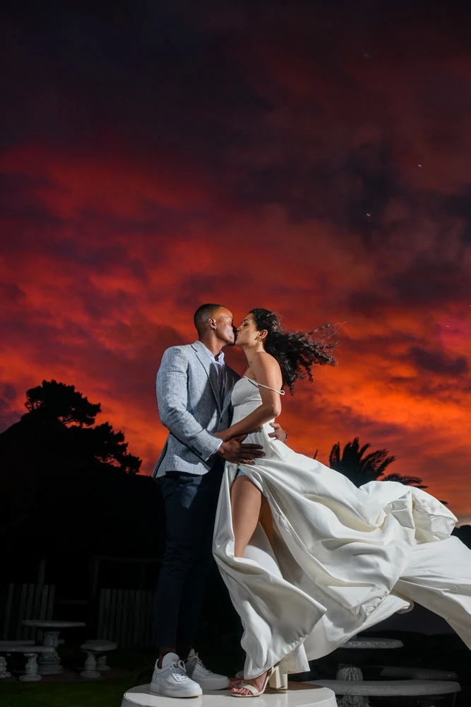couple kissing fiery red sky dress flowing wind