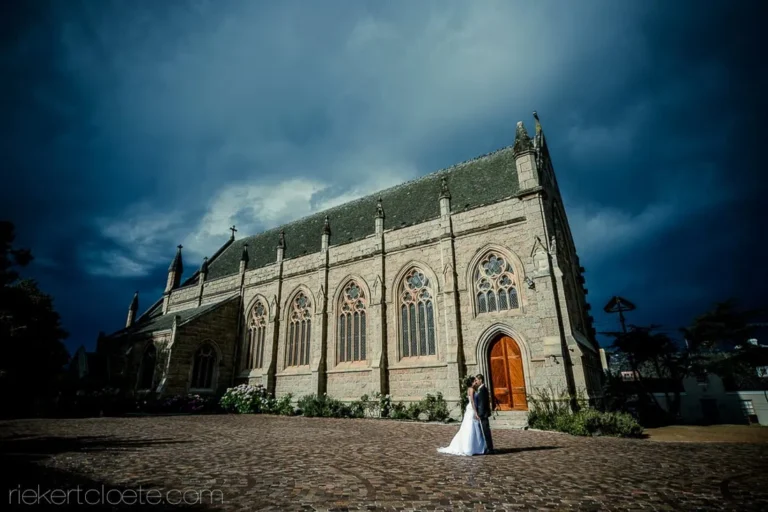 couple kissing outside gothic stone church dramatic sky