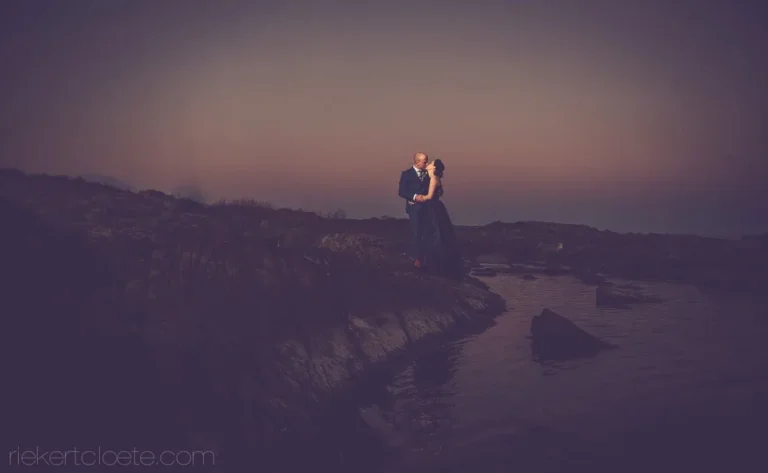 couple kissing rocky coastal cliff ocean dusk