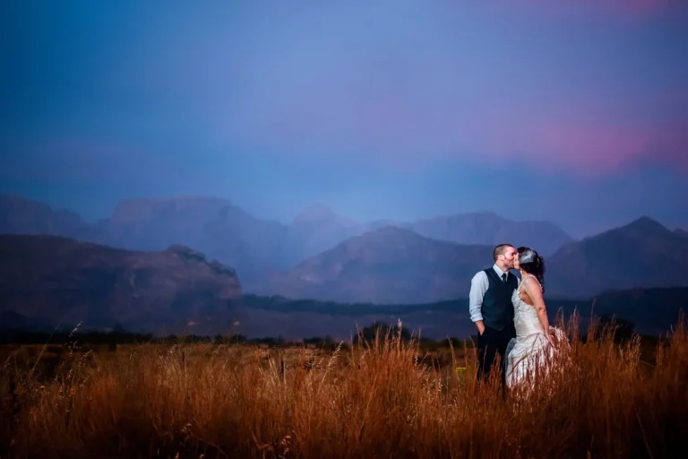 couple kissing wheat field dramatic blue mountains