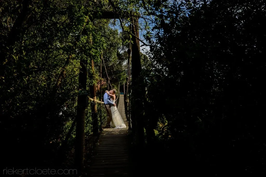 couple kissing wooden bridge lush green forest