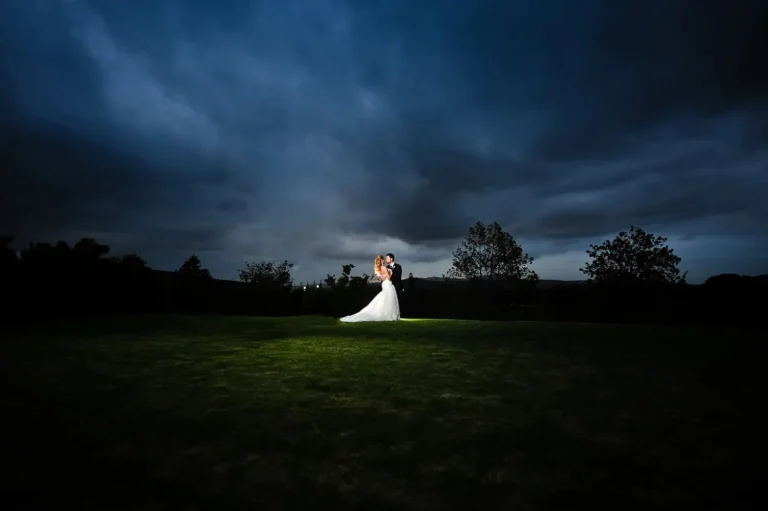 couple lit green lawn night dramatic storm clouds