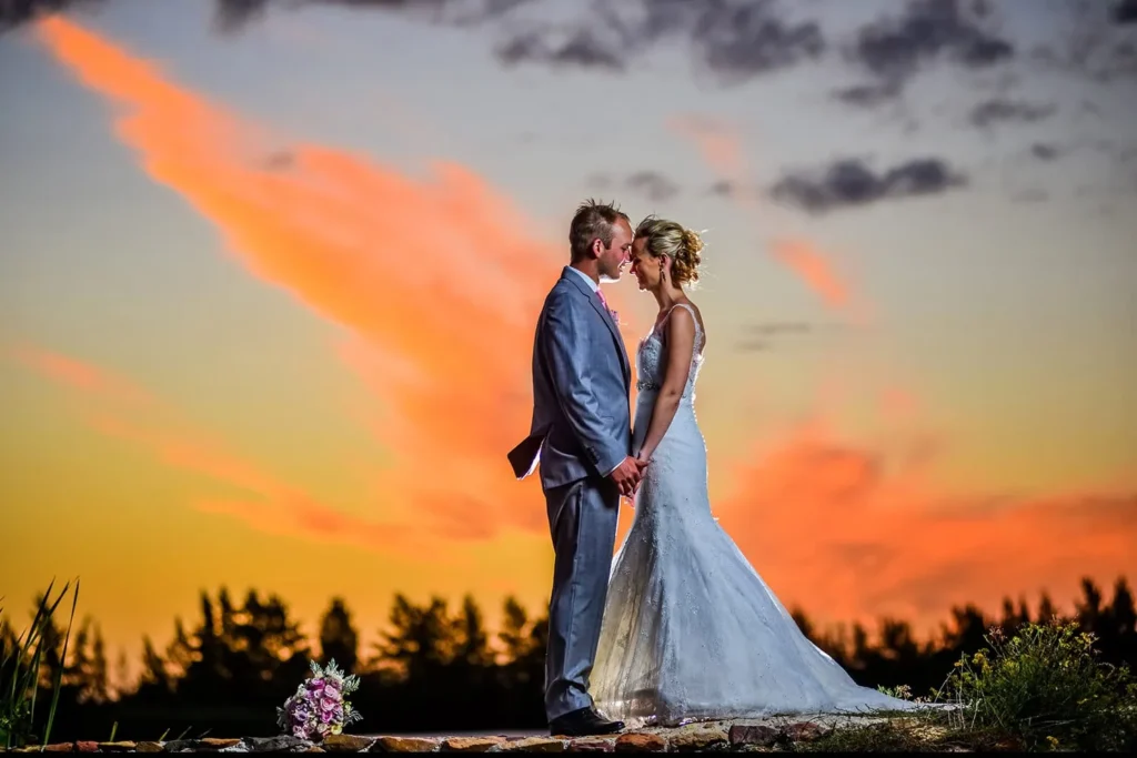 couple romantic pose vibrant orange sunset treeline