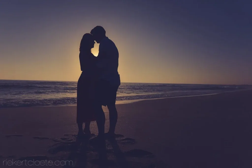 couple silhouette touching foreheads beach sunset