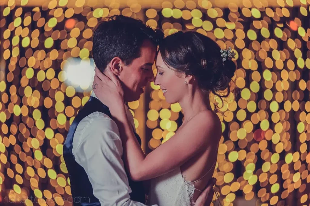 couple touching foreheads golden bokeh fairy lights