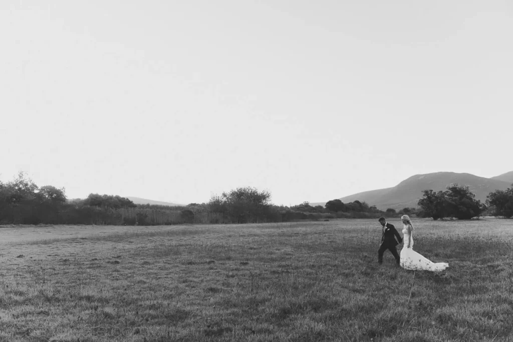 couple walking open field mountain backdrop