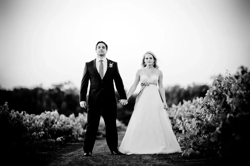 couple walking vineyard rows black white portrait
