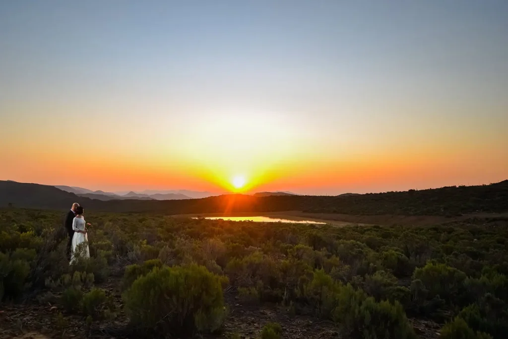 couple watching sunset over dam fynbos landscape