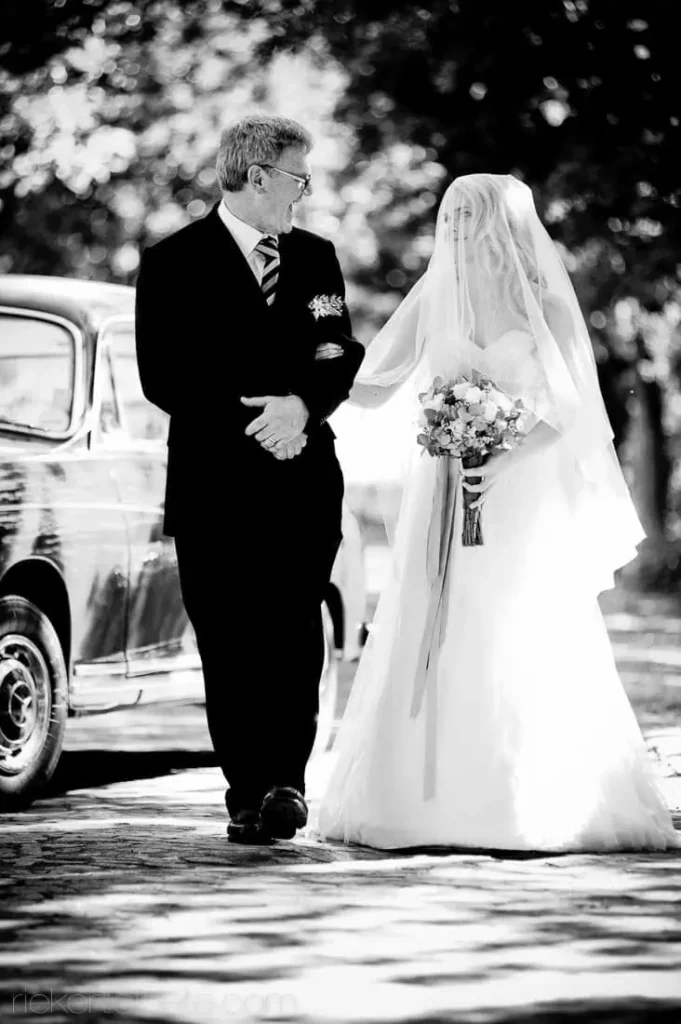 father walking veiled bride vintage car cobblestone