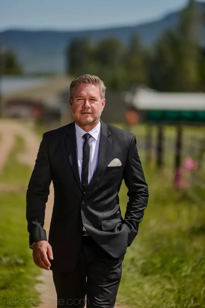groom black suit walking farm track mountains