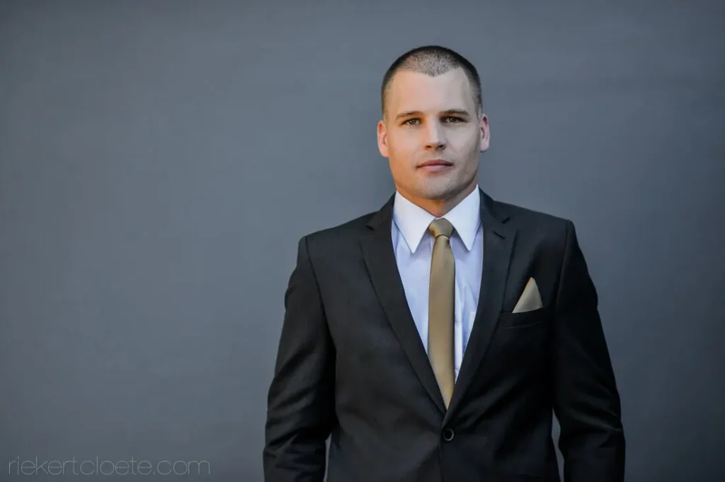 groom charcoal suit gold tie grey wall portrait